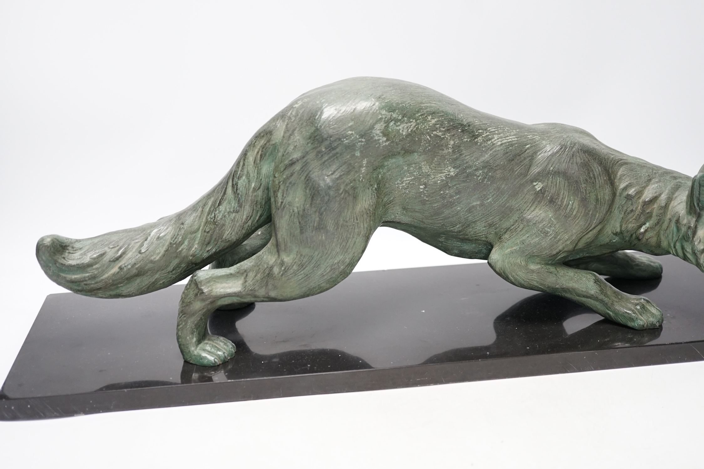 A bronzed metal model of a stalking fox, on black marble plinth, 62cm